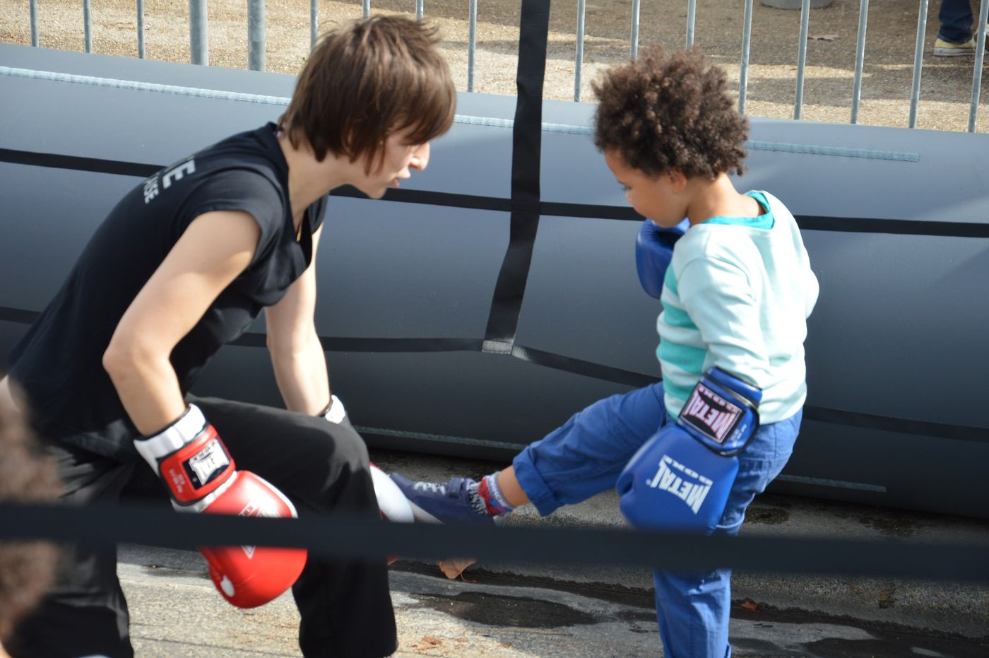 Une éducatrice accompagne un enfant qui lance un coup de pied, gants aux mains