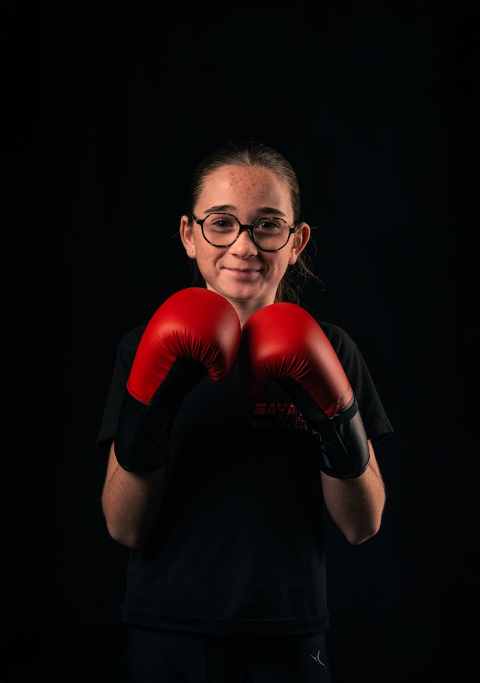 Une jeune pratiquante sourit, gants rouges en garde