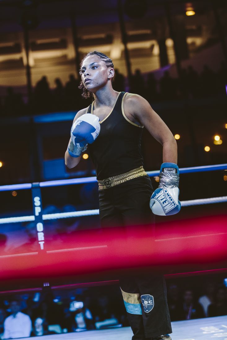 Une tireuse en garde sur le ring, sous les projecteurs