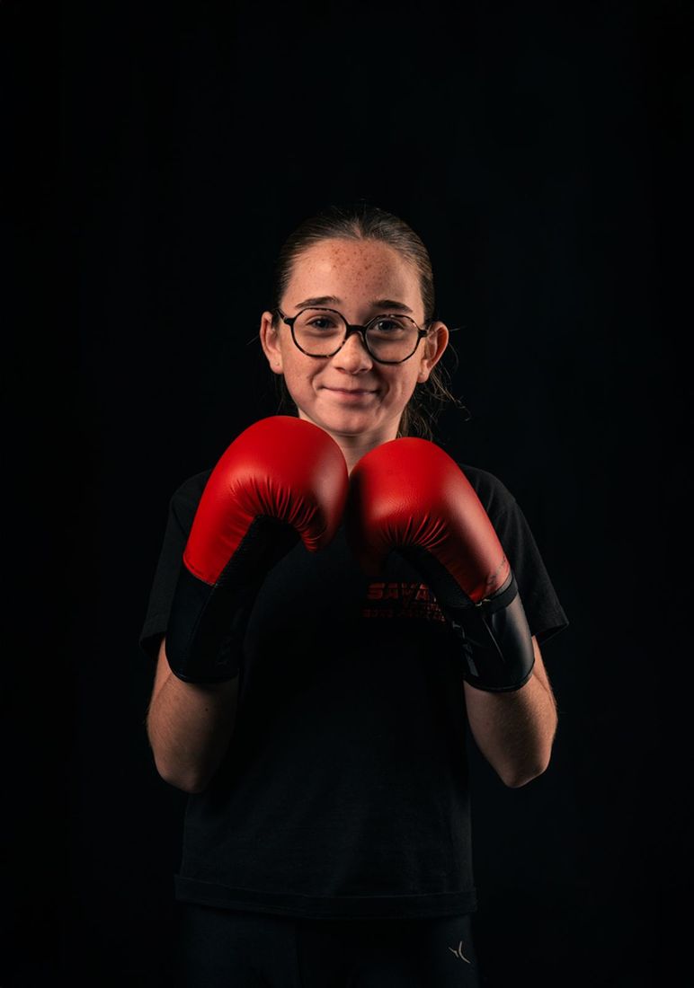 Une jeune pratiquante sourit, gants rouges en garde