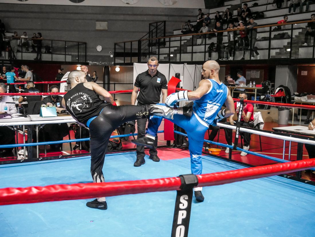 Coup de pied de face sur un ring bleu, tribunes pleines