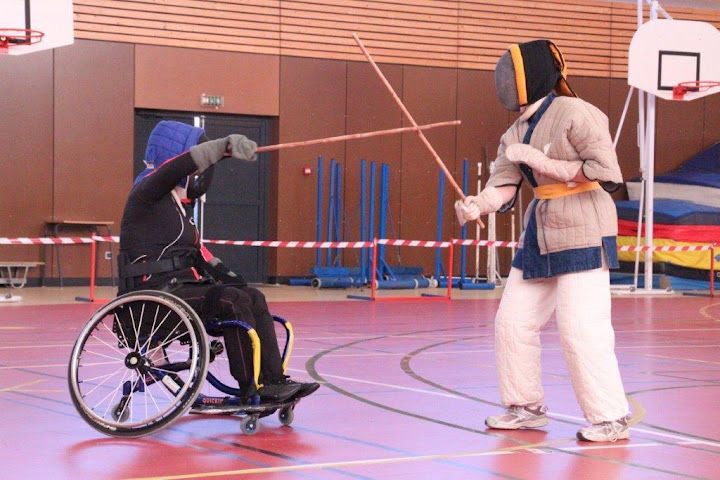 Un tireur en fauteuil roulant face à un tireur debout, en canne de combat