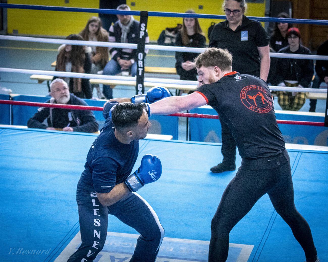 Deux tireurs en garde échangent sur un ring bleu