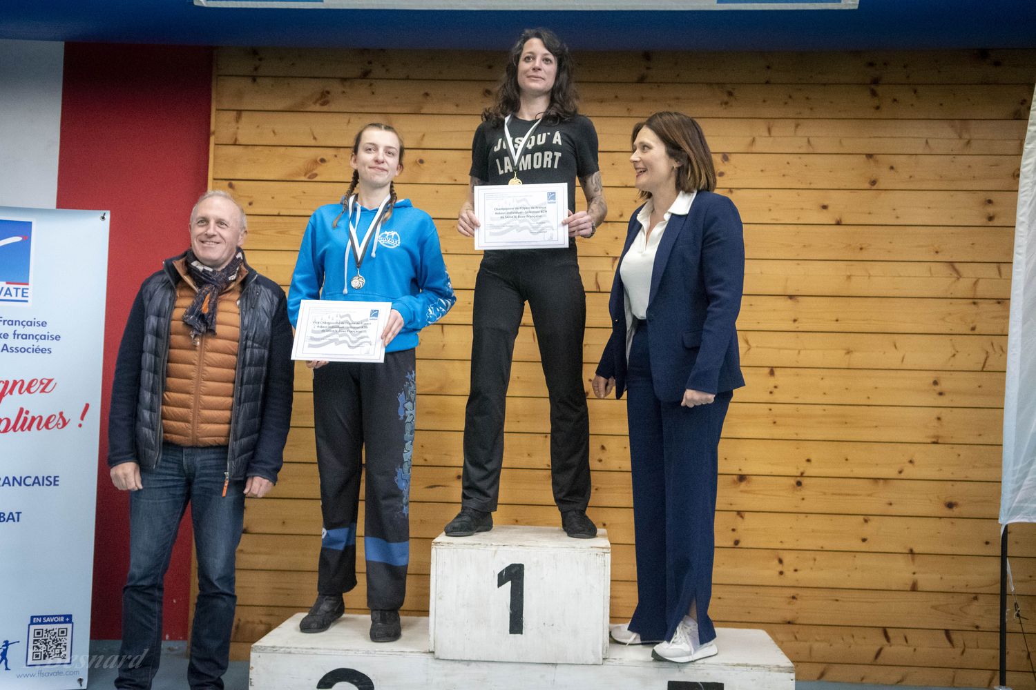 Podium féminin, diplômes en main, entouré d’officiels